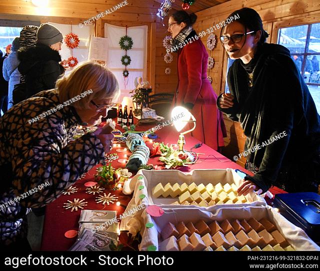 16 December 2023, Saxony, Schkeuditz: Visitors stand at a stall selling handmade soap and jewelry at the Victorian Christmas Market at Biedermeierstrand in...