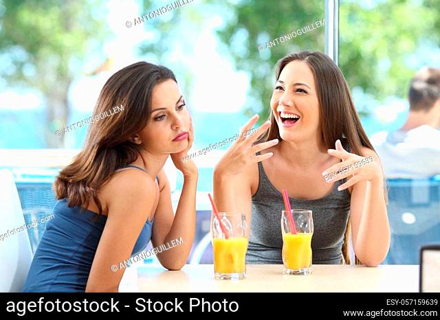 Bored woman suffering a bad conversation from a friend in a coffee shop or hotel on the beach