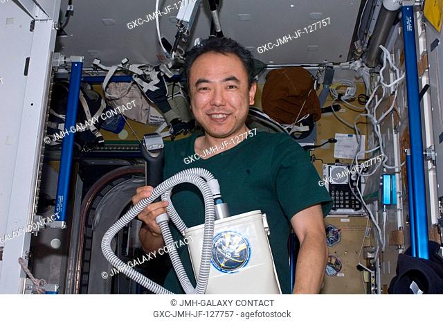 Japan Aerospace Exploration Agency astronaut Satoshi Furukawa, Expedition 28 flight engineer, holds hair clippers attached to a vacuum cleaner in the...