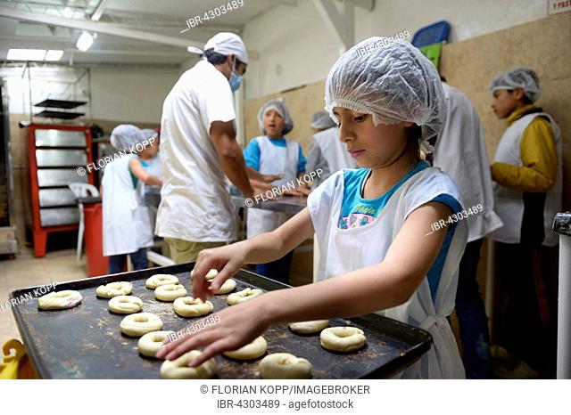 Girl placing raw dough rings onto tray, Bäckerei, vocational training, Creciendo Unidos social project, Villa Javier, Bogotá, Colombia