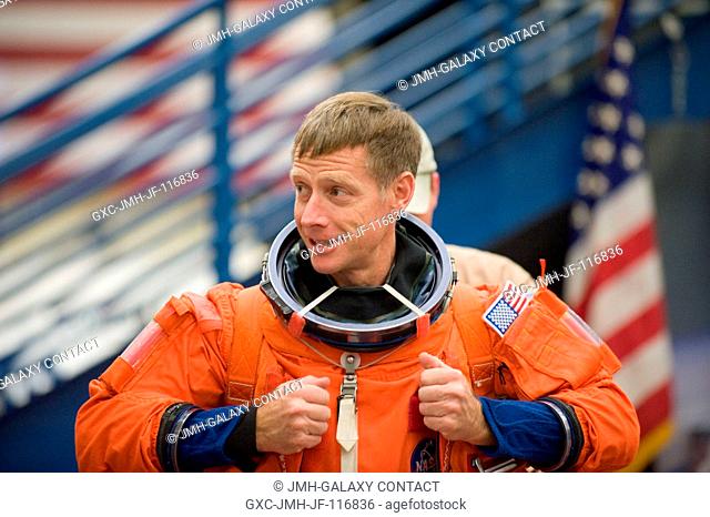 NASA astronaut Chris Ferguson, STS-135 commander, dons a training version of his shuttle launch and entry suit in preparation for an emergency egress training...
