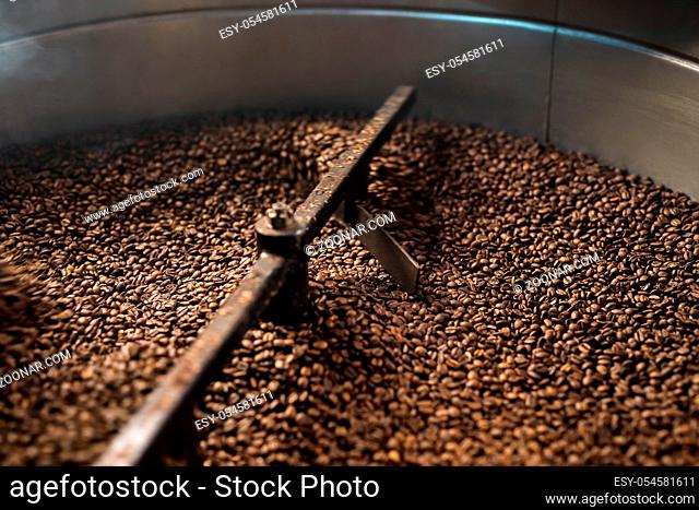 Machine for roasting coffee beans called roaster with a special automatic mixing device at work in a production room