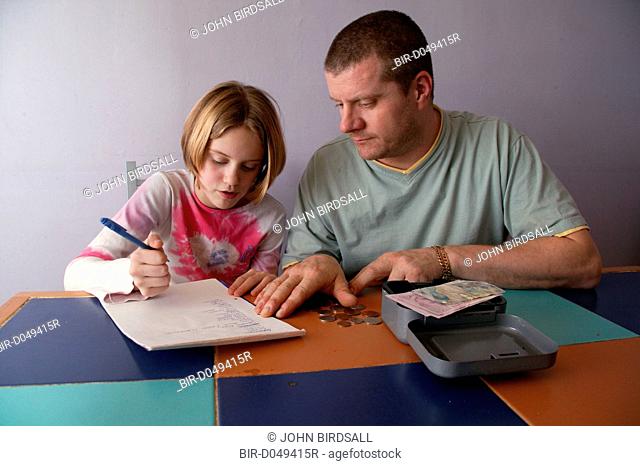Single parent and young daughter making a shopping list and counting money