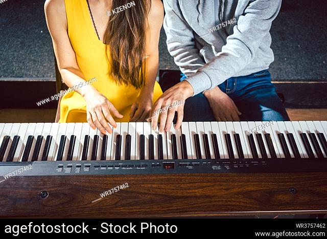 Piano teacher giving lessons to his student in music school