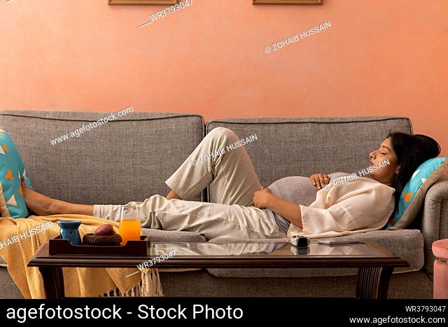 Pregnant woman sleeping on sofa at hone