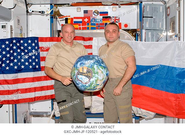 NASA astronaut Jeffrey Williams (left), Expedition 22 commander; and Russian cosmonaut Maxim Suraev, flight engineer, hold a globe with the Expedition 22 logo...