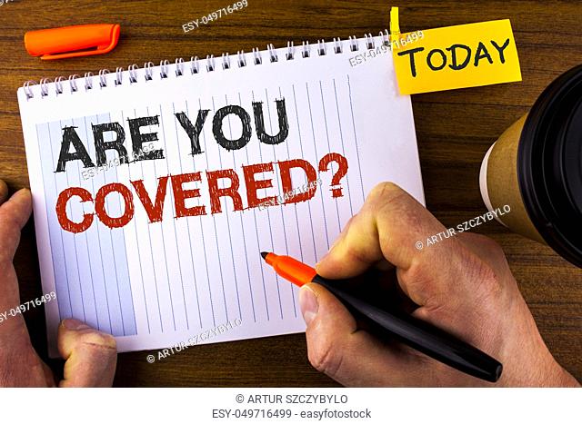 Text sign showing Are You Covered Question. Conceptual photo asking about you insurance health statement written by Man Notepad holding Marker Wooden background...