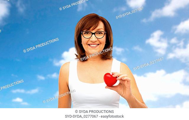 portrait of smiling senior woman holding red heart