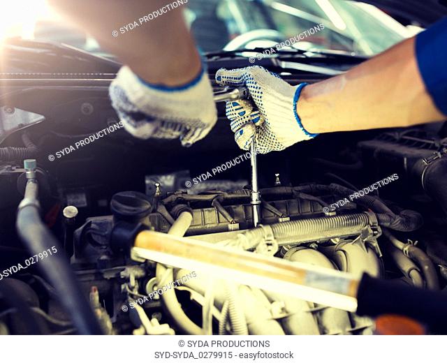 mechanic man with wrench repairing car at workshop