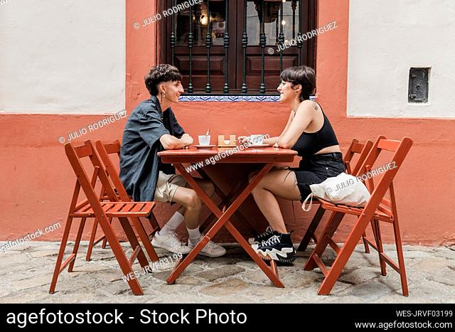 Smiling man talking with girlfriend at sidewalk cafe