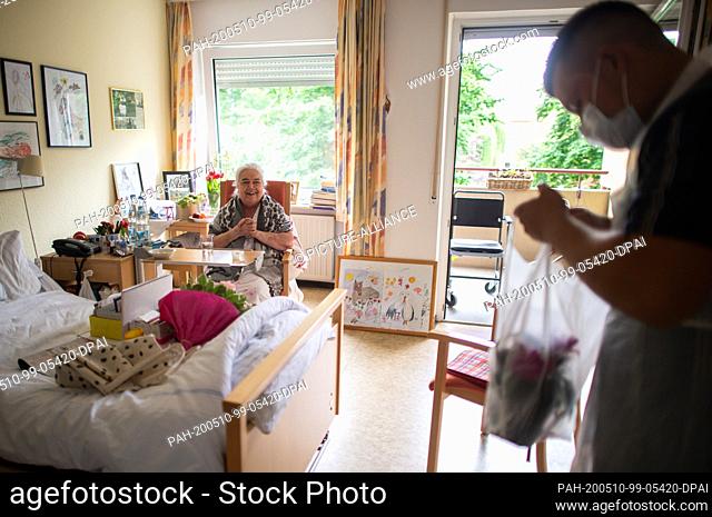 10 May 2020, North Rhine-Westphalia, Heinsberg: Lars Dressen (r) hands over a bouquet of flowers to his grandmother Elisabeth Djata (l) in the...