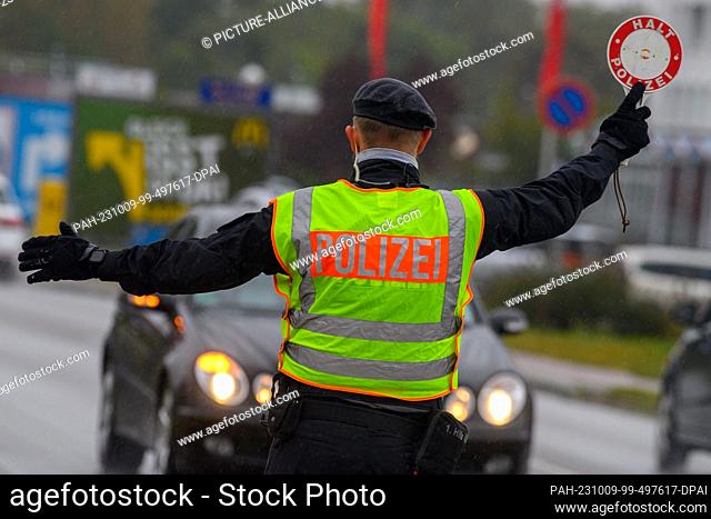 09 October 2023, Saxony-Anhalt, Stendal: A police officer waves a motorist out of traffic with a police ladle. Saxony-Anhalt's state police are taking part in...