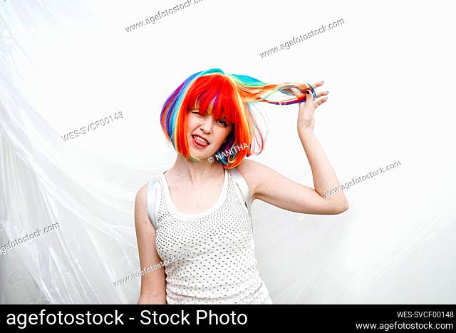 Playful woman with hand in hair by plastic backdrop