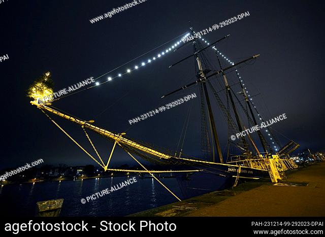 14 December 2023, Mecklenburg-Western Pomerania, Rostock: The Santa Barbara Anna, decorated for Christmas, is moored in the city harbor