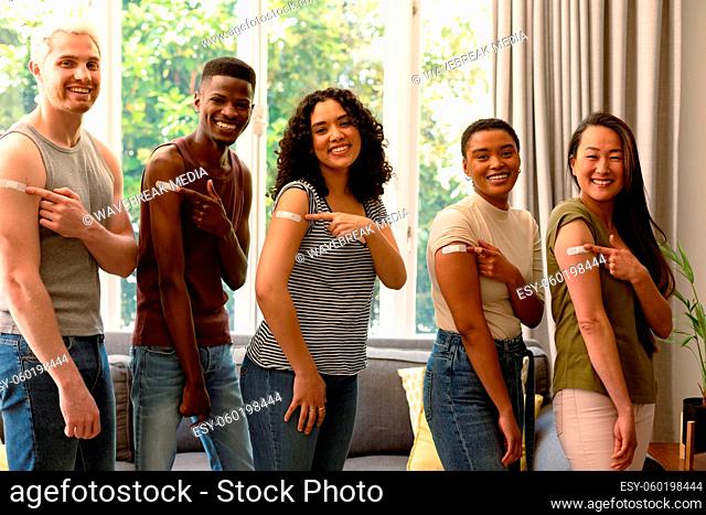 Group of happy diverse female and male friends showing plasters after vaccination
