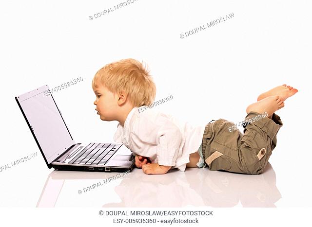 Young boy looking at a laptop on a stool. Isolated on white background