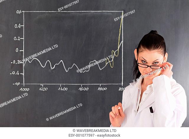 Dark-haired scientist standing near the blackboard and looking at the camera