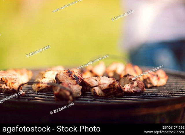 Tasty meat frying on grill. Delicious looking chicken meat getting cooked on grill outdoors in sunny weather