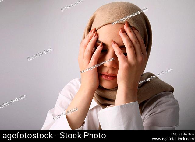 Close-up of Arabian young woman wearing hijab, isolated on white wall. Horizontal
