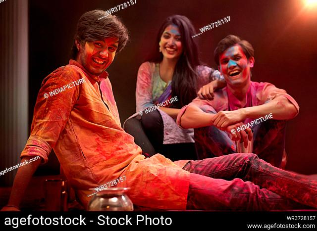 A GROUP OF FRIENDS SITTING TOGETHER AND POSING DURING HOLI FESTIVAL