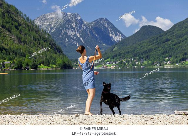 Woman playing with her dog on the shore of lake Grundlsee, Hoher Sarstein, Salzkammergut, Styria, Austria