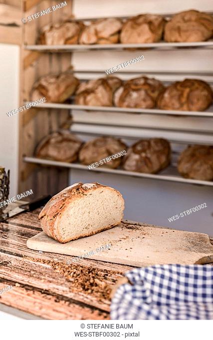 Half of fresh brown bread on wooden board