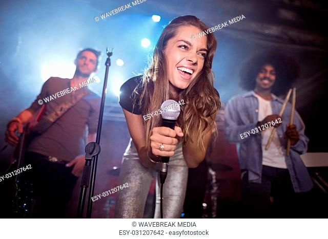 Cheerful young woman with musicians performing at nightclub
