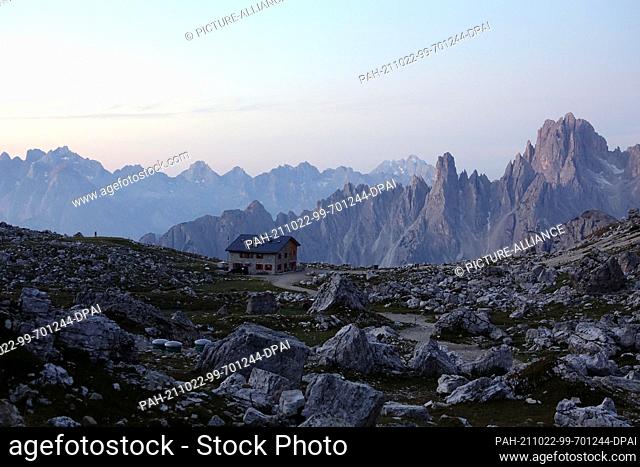 05 October 2021, Italy, Sexten: The Lavaredo Hut at the Three Peaks (Italian: Tre Cime di Lavaredo) in the Sesto Dolomites at sunrise
