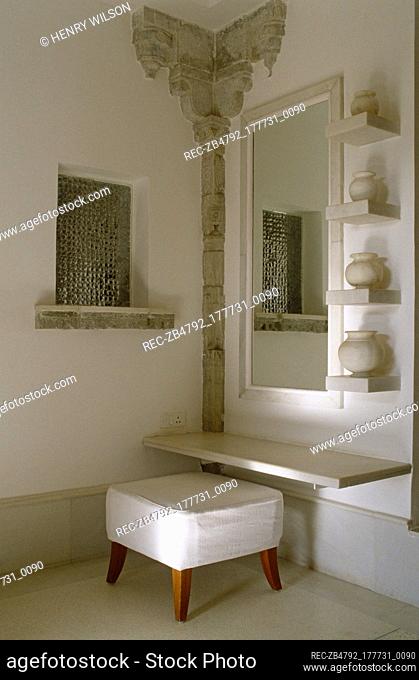 Upholstered stool below mirror in ethnic styled room