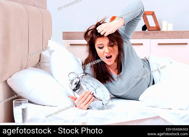 The young woman lying on the bed in time management concept