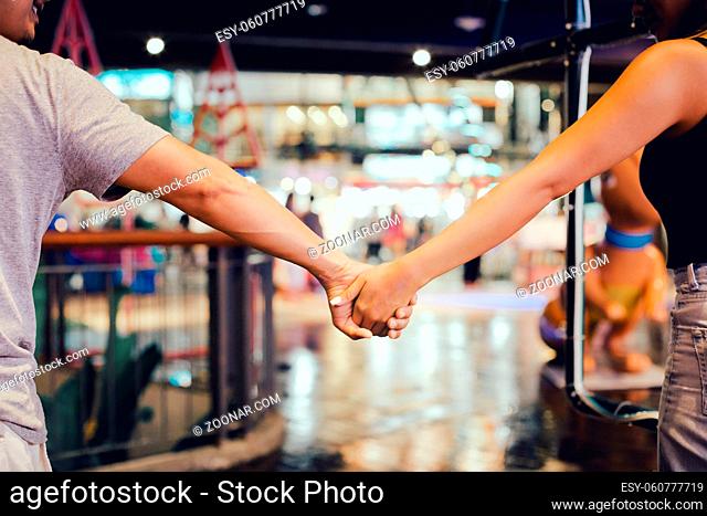 Cropped image of couple holding hand and walking outdoors in shopping mall