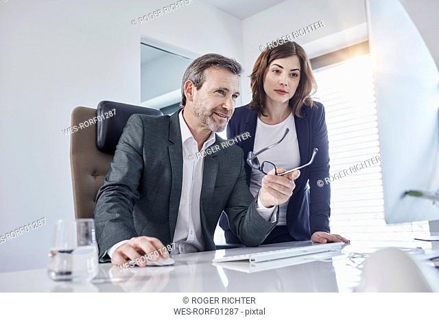 Businessman and businesswoman discussing at desk in office