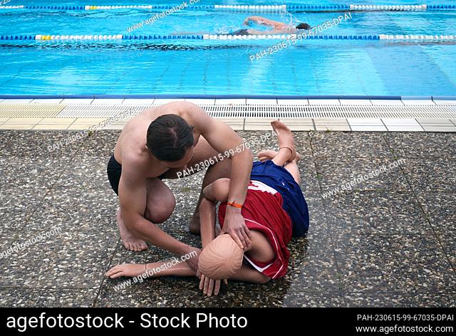 14 June 2023, Berlin: 25-year-old Alexander demonstrates the methods of resuscitating a casualty (stable lateral position) on a manikin during the pre-swim of...