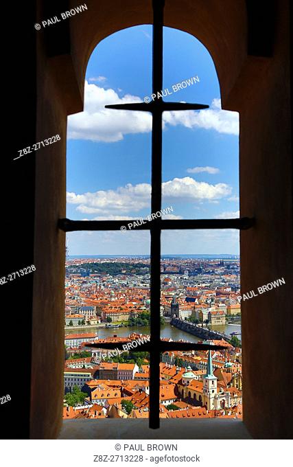 General city skyline view of Prague and the Vtlava River seen through an arched window of St Vitus Cathedral, Czech Republic