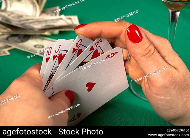 poker cards on green table with dollars and a drink