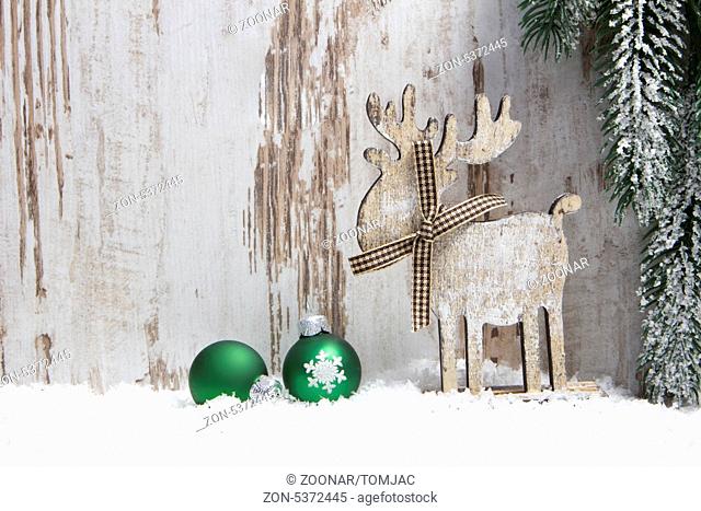 christmas decoration with wood background, snow, elk, christmas baubles green and fir branch
