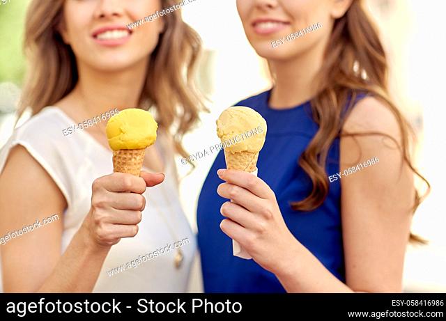 close up of happy women eating ice cream in city