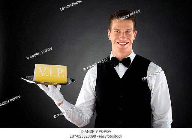 Young Happy Waiter Showing Vip Sign On Tray