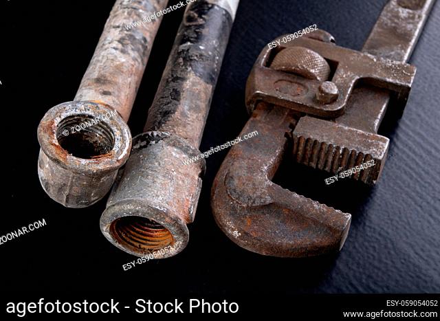 Old dirty pipe and hydraulic wrench. Accessories and tools for a plumber. Dark background