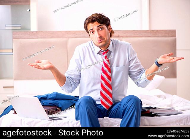 Young employee working at home sitting on the bed
