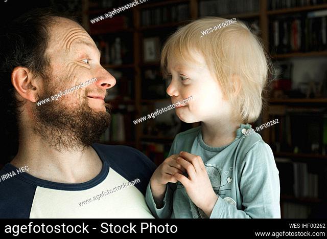 Father grimacing at little daughter at home