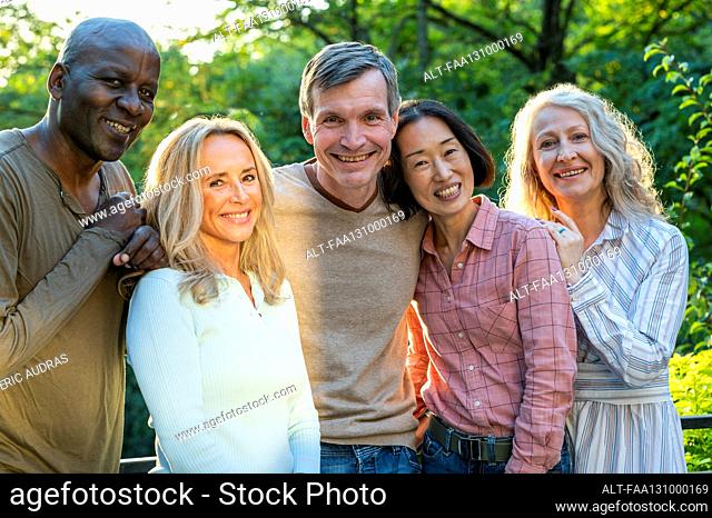 Group of diverse happy senior friends posing for photo outdoors at sunset