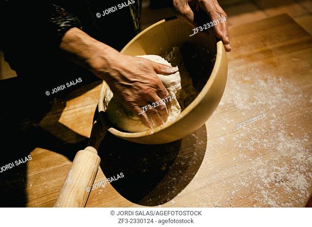 Hands kneading wheat bread dough on a wooden table