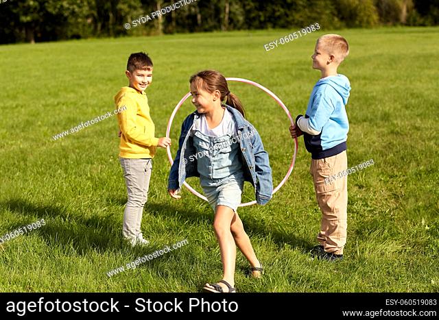 happy children playing game with hula hoop at park
