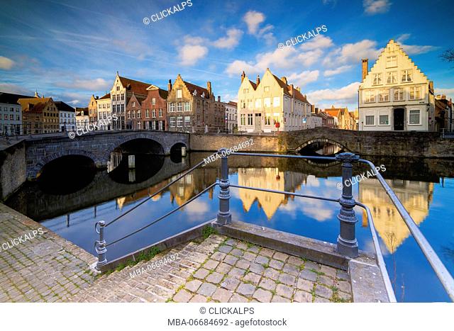View of the typical buildings reflected on the canal at sunrise from a terrace on the quay Bruges West Flanders Belgium Europe