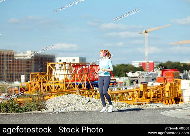 Young woman jogging at construction site