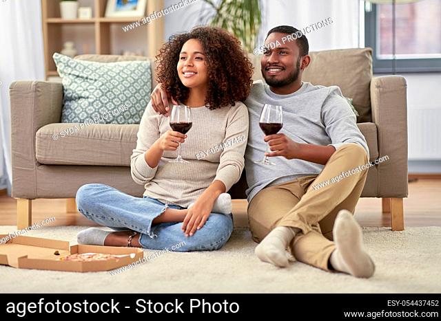 happy couple with wine and takeaway pizza at home