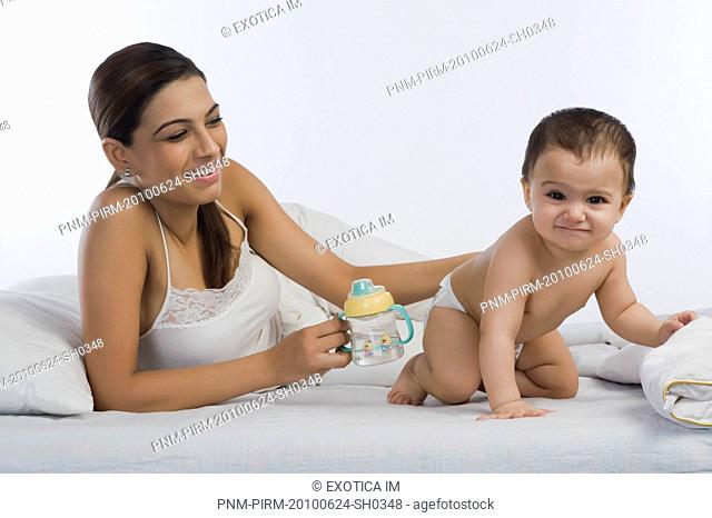 Woman feeding water to her son on the bed
