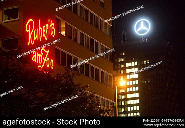 PRODUCTION - 28 August 2022, Berlin: The illuminated sign ""Ruhesitz am Zoo"" shines next to the Mercedes-Benz logo on Kurfürstenstraße