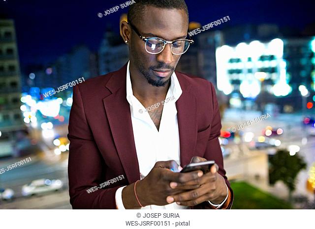 Young entrepÇ¬reneur wating on hotel terrace for his appointment, using smartphone